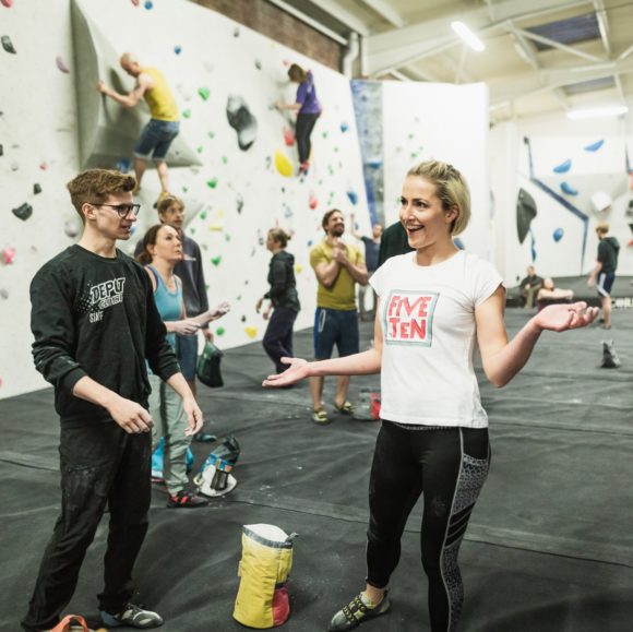 Depot Climbing Members stand talking on the mats with climbers behind them