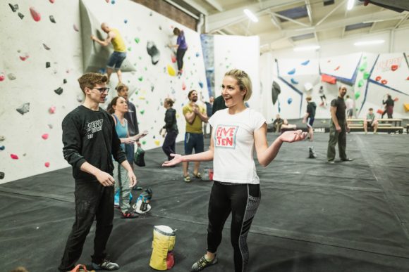 Depot Climbing participants talk on the mats while climbers climb behind them