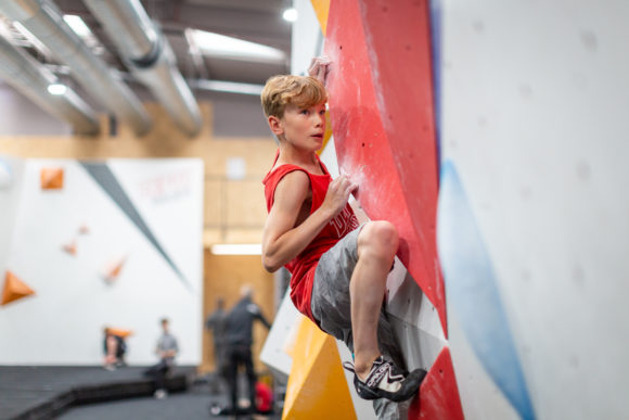 a boy bouldering at a climbing centre