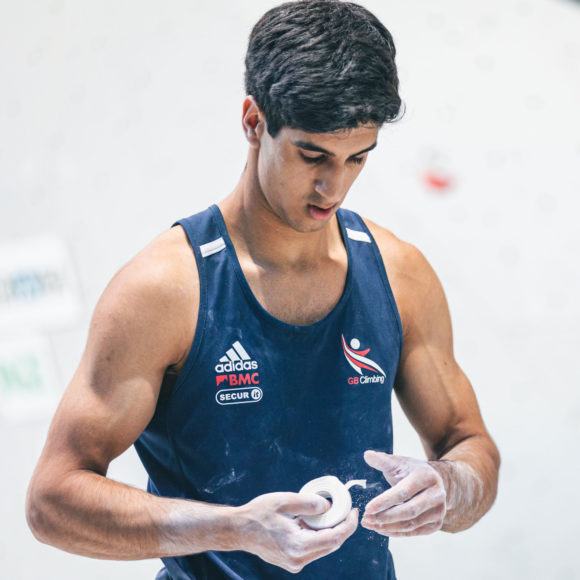 Dayan Akhtar is wearing a GB Climbing vest and looking down as he applying tape to his fingers