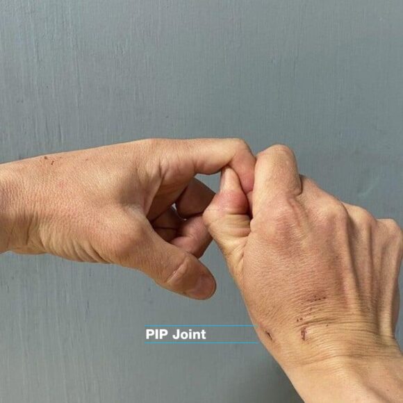 PIP joint climbing physio movement. The right hand is gently stretching the left hand pip joint of the index finger.