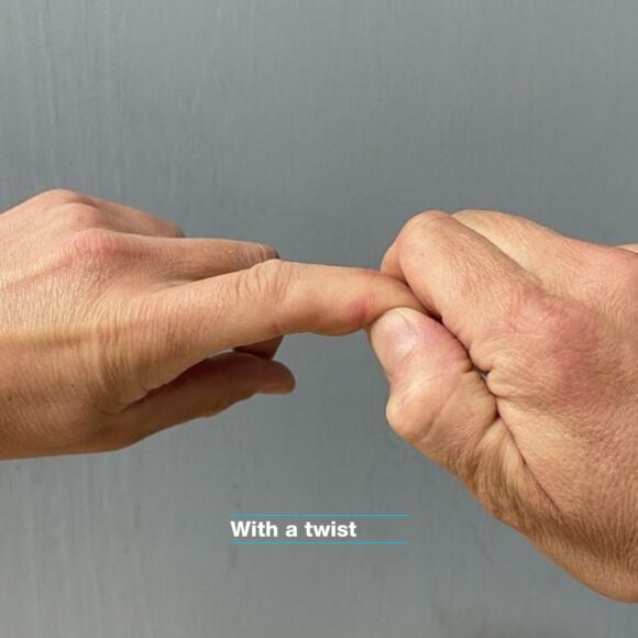 DIP joint climbing physio movement. The right hand is gently stretching the left hand dip joint with a mild twiest of the index finger.