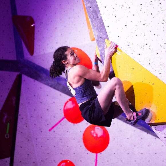 Zoe Peetermans powerfully grips on to crimps on a volume in a compression style with high bunched feet.